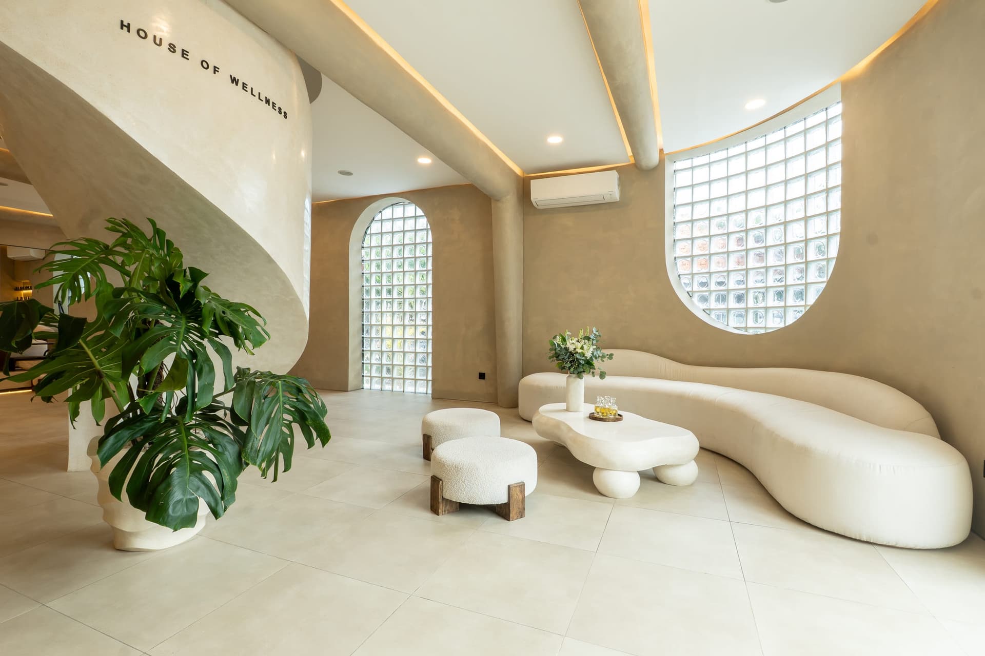 The GLAZE reception lounge with curved bouclé sofas and a glass-block window.