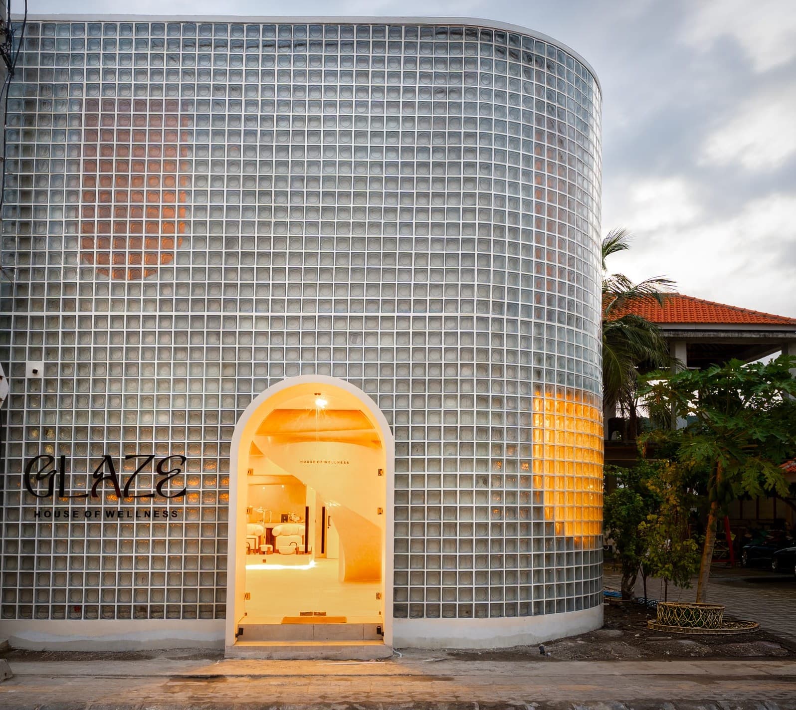 The GLAZE glass-block House of Wellness, glowing at dusk